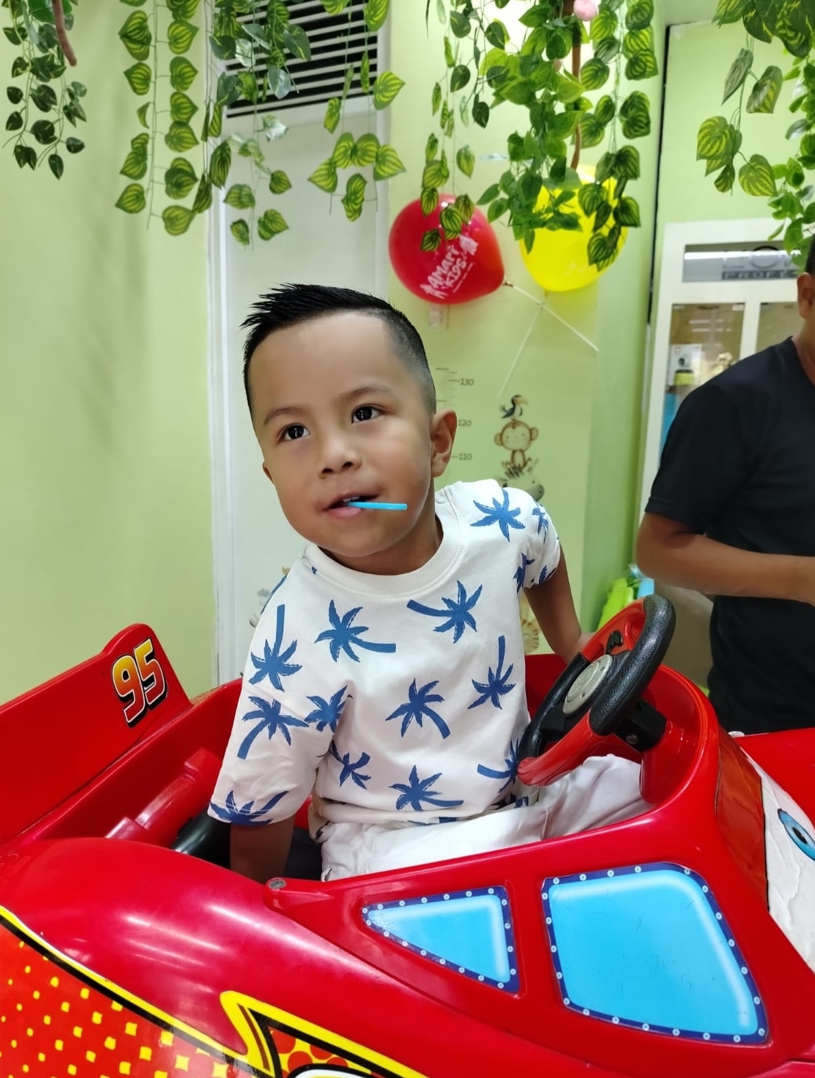 Niño sonriente en auto infantil rojo en AmariKids