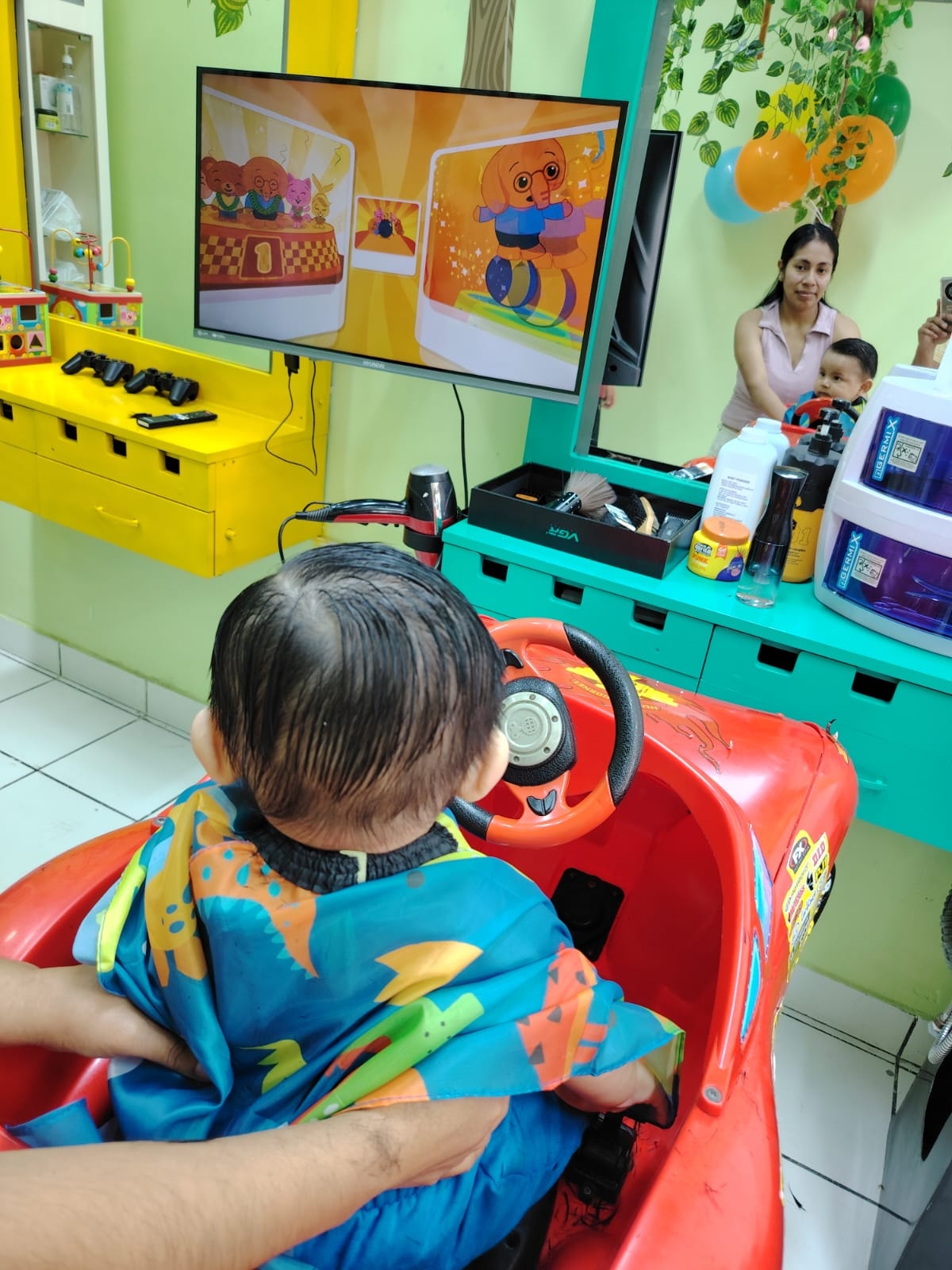 Niño disfrutando dibujos mientras recibe su corte