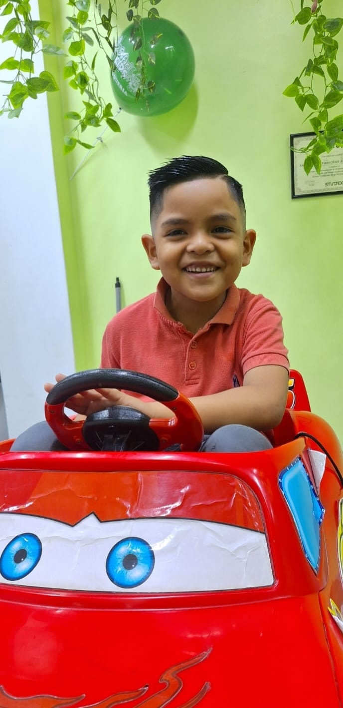 Niño sonriente en un auto infantil rojo en AmariKids