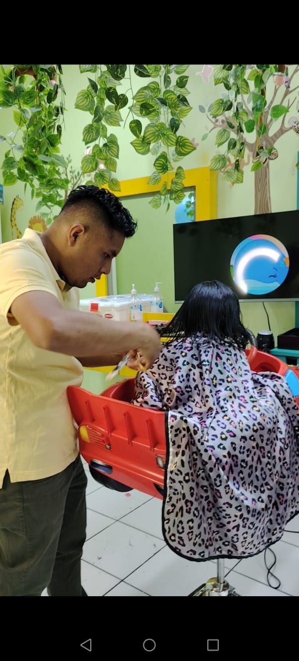Estilista realizando un corte en silla auto infantil